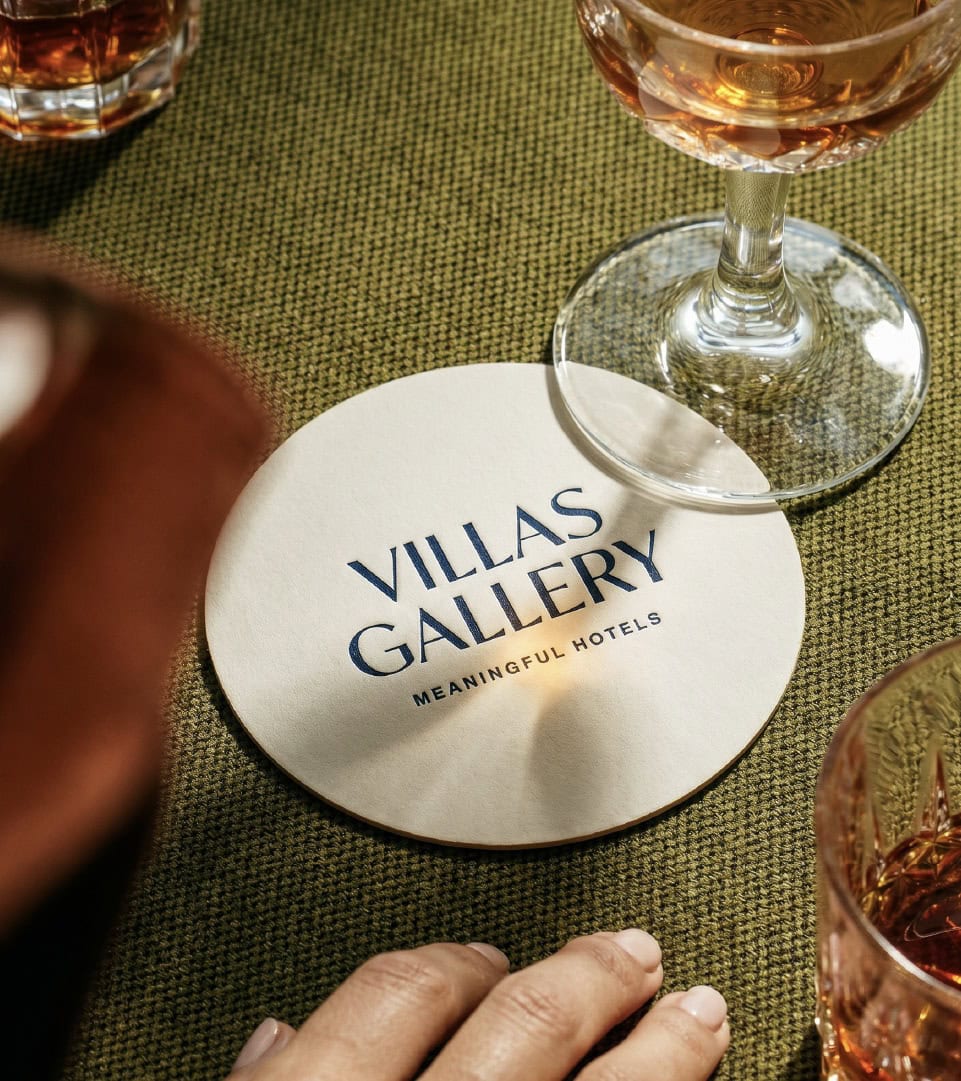 Logo de Villas Gallery en una mesa con copas de vino.