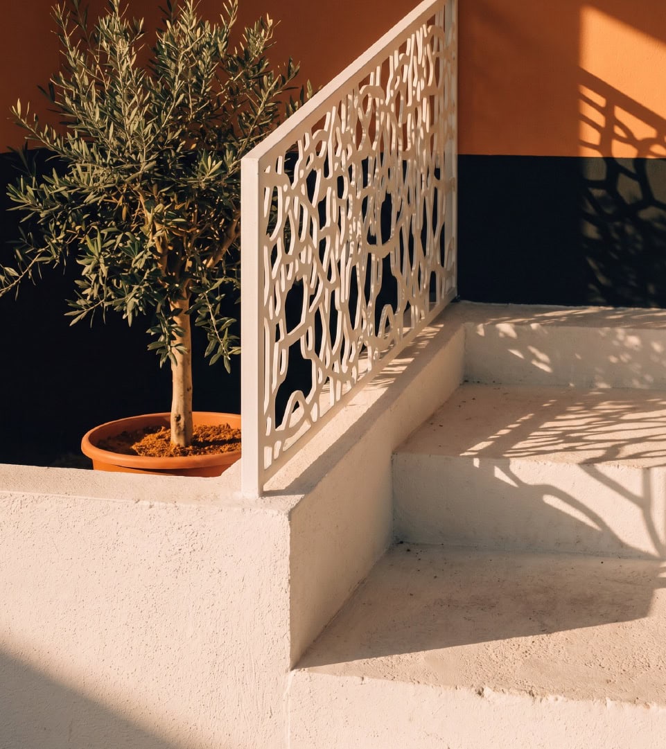 Balcón con barandilla decorativa y planta en maceta en un entorno moderno.