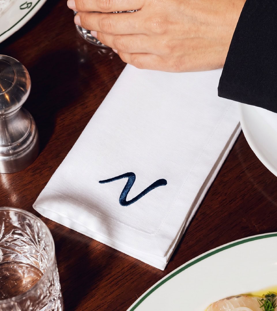 Mano con servilleta personalizada en restaurante premium.