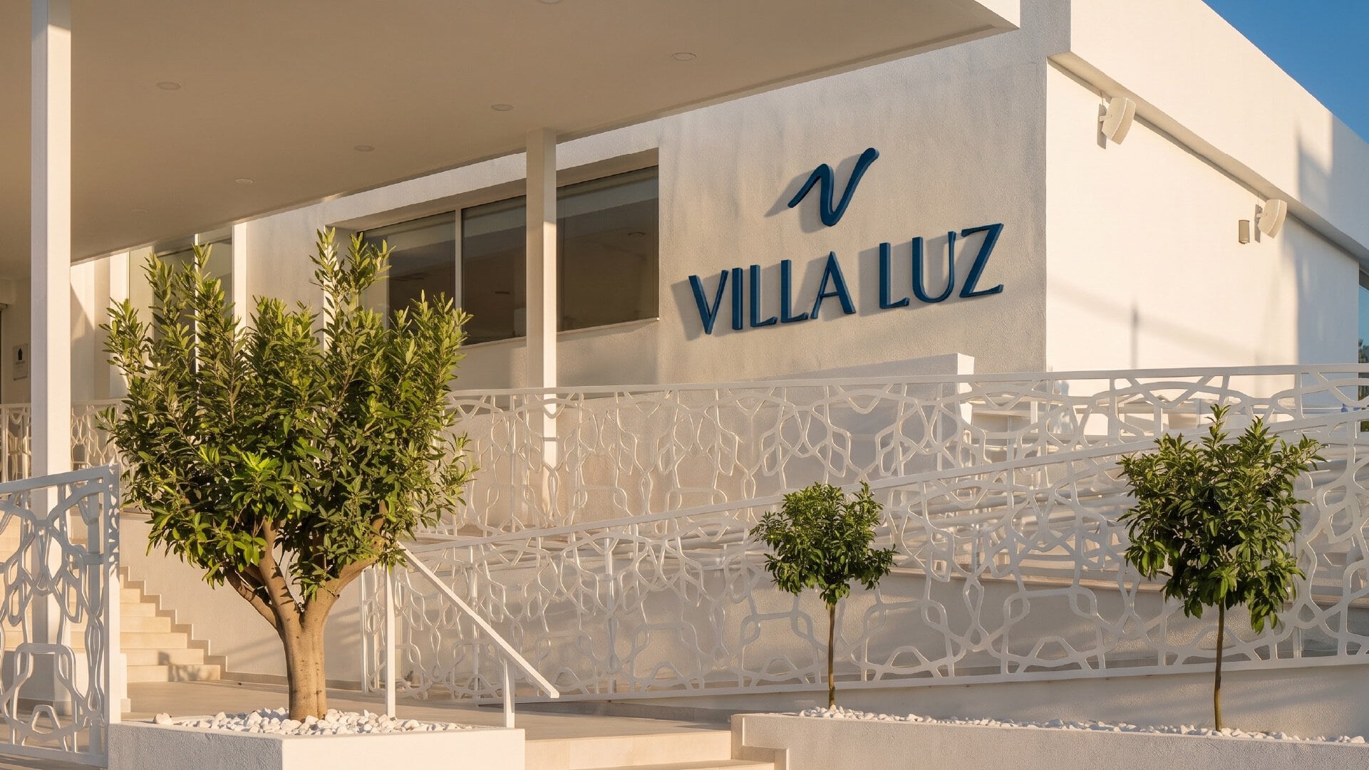 Fachada moderna de Villa Luz con señalización de marca clara y elegante.